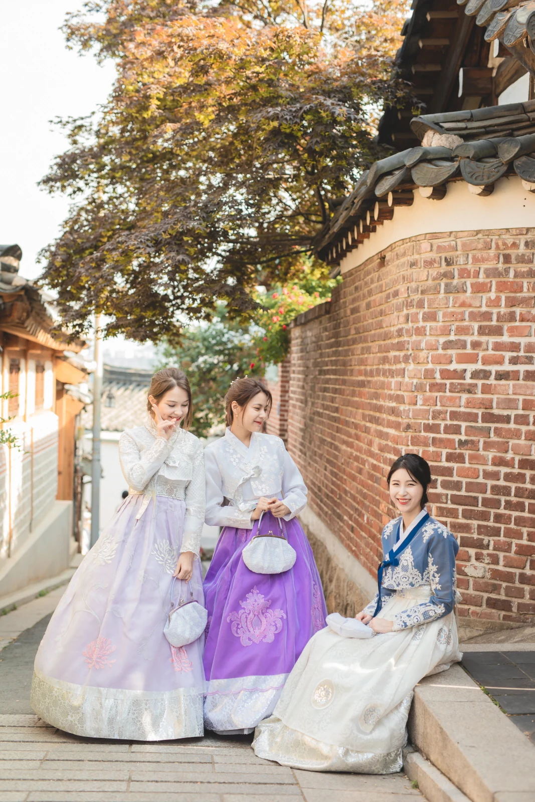 보랏빛 한복을 입고 한옥 골목에 앉은 친구들