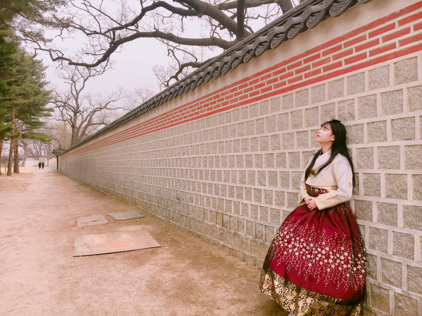 고궁 돌담길에서 한복을 입고 서 있는 사람